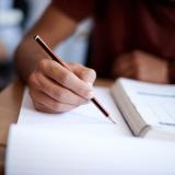 Closeup shot of a young man writing on a note pad Closeup shot of a young man writing on a note pad